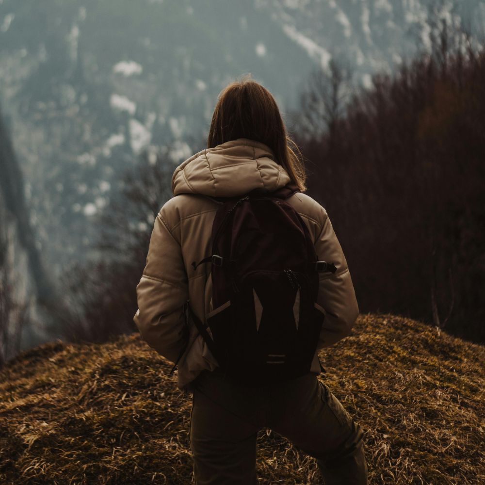 Person with a backpack standing on a mountain trail